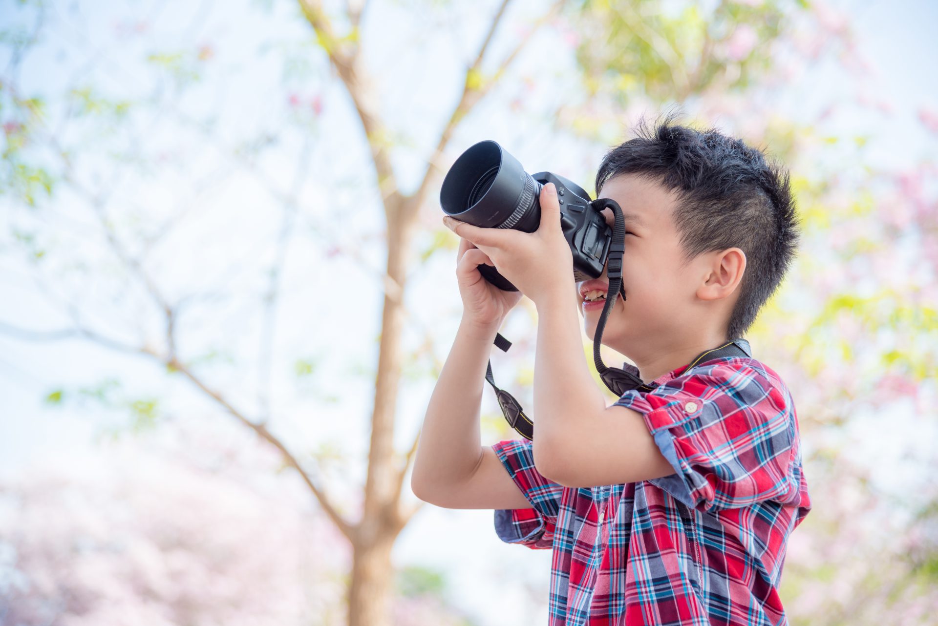 cute boy photographing with digital camera park